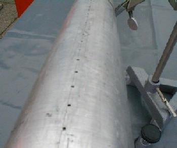 Metal tube with long row of drilled holes